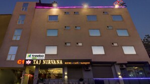 A multi-story building with a sign for 'Taj Nirvana' indicating it offers rooms, café, and banquet services. - Treebo C1 Taj Nirvana (Agra)