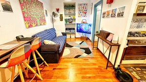 A cozy living room with a sofa, a coffee table, a TV, and a kitchen area with a stove. - Meizon Genoa - 5 minutes from the station, the sea, the subway (Genova)
