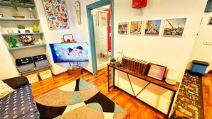 A living room with a TV, books, and a red birdhouse on the wall. - Meizon Genoa - 5 minutes from the station, the sea, the subway (Genova)