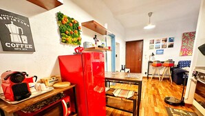 A compact kitchen with a red refrigerator, wooden flooring, and a wall-mounted coffee-themed decoration. - Meizon Genoa - 5 minutes from the station, the sea, the subway (Genova)