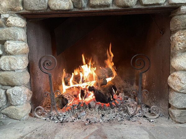 A stone fireplace with a fire burning inside. - Lakefront Home Rare & extraordinary with 250ft sandy beach. Privacy. (Weld)