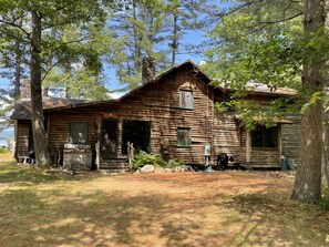 A rustic log cabin with a chimney, a front porch, and a small deck area. - Lakefront Home Rare & extraordinary with 250ft sandy beach. Privacy. (Weld)