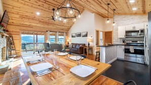 A wooden interior with a dining area, kitchen, and seating. - STUNNING SMOKY MOUNTAIN VIEWS! Hot Tub! Games! Close to Dollywood and Parkway! (Sevierville)