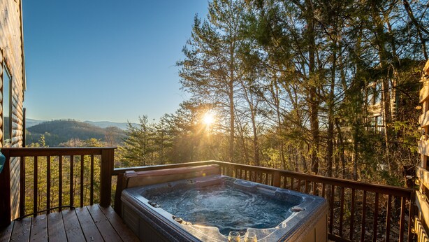 A hot tub on a wooden deck with a view of a forest and mountains. - STUNNING SMOKY MOUNTAIN VIEWS! Hot Tub! Games! Close to Dollywood and Parkway! (Sevierville)