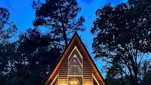 A triangular wooden cabin with a central skylight, a chandelier, and a door. - Amazing A-Frame Cabin, Modern Luxury Oasis on a Pond (Pittsboro)