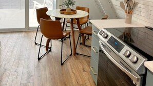 A modern kitchen with a built-in oven and a dining area with a round table and chairs. - Amazing A-Frame Cabin, Modern Luxury Oasis on a Pond (Pittsboro)