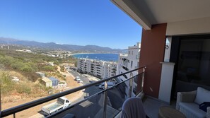 Un balcón con vistas a la costa, que incluye edificios y una playa.