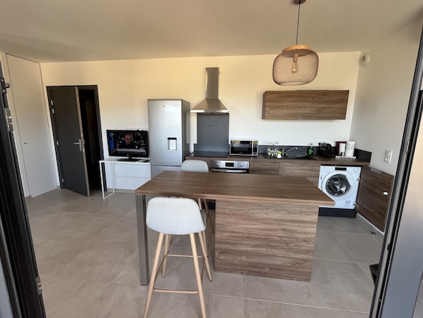 Una cocina moderna con una isla de madera, electrodomésticos integrados y una lámpara colgante.