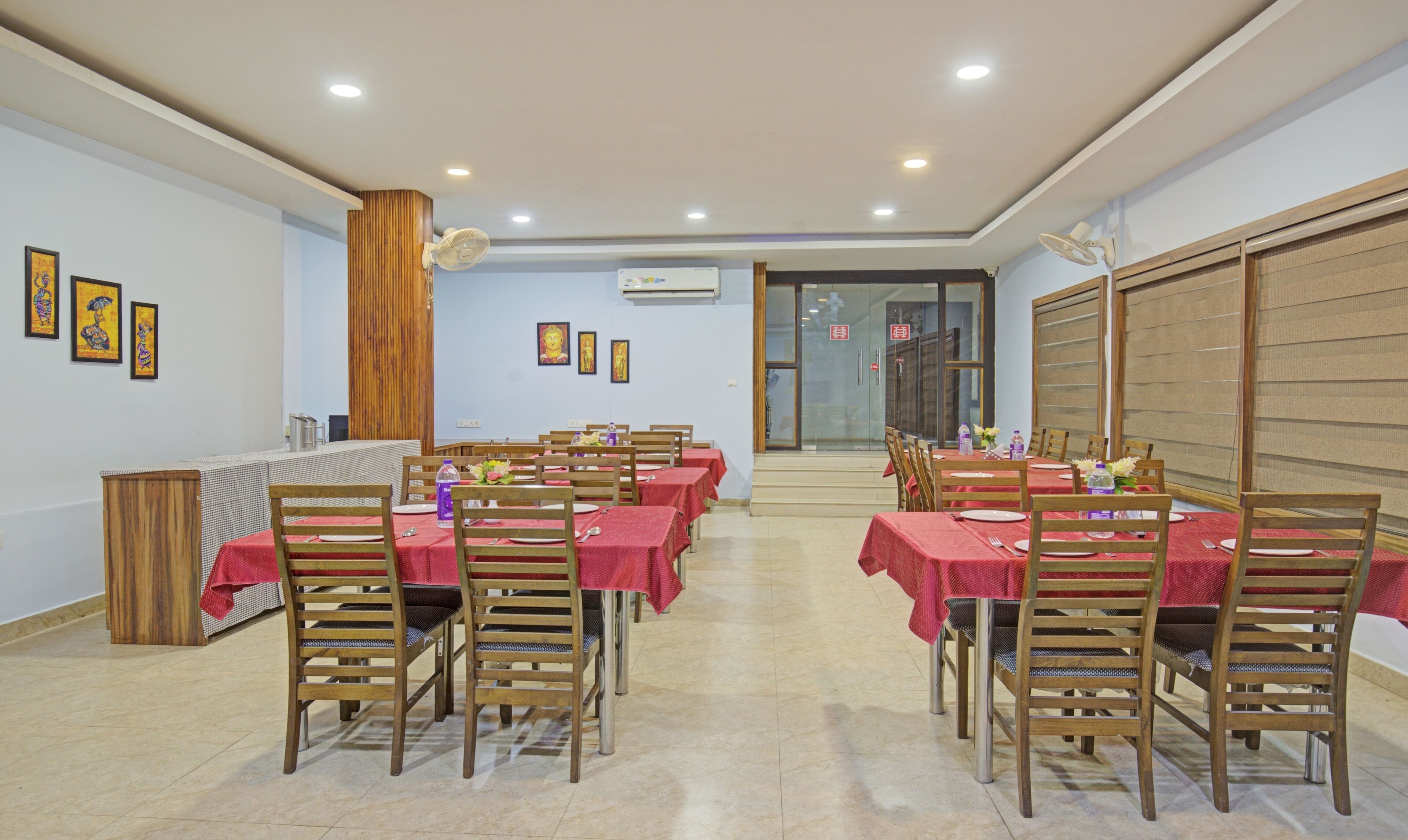 A dining area with multiple tables and chairs, wooden paneling on the walls, and ceiling fans.
