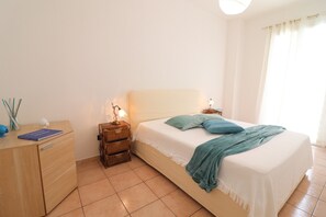 A bedroom with a bed, a nightstand, a dresser, and a lamp.
