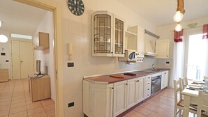 A kitchen with white cabinets, a wooden countertop, a microwave, and a dining area with a table and chairs. - Casa Carlotta in Otranto: Balcony, Wi-Fi & Air Conditioning (otranto)