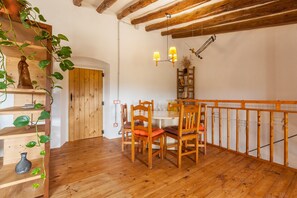 A wooden dining table with chairs, a wooden railing, and a wooden floor.