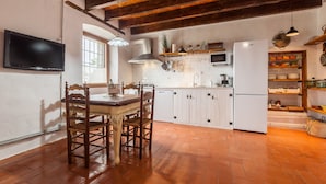 A kitchen with wooden flooring, white cabinets, a built-in microwave, and a refrigerator. - Holiday Home 'Romegosa Benestar' with Mountain Views, Wi-Fi, and Air Conditioning (Sant Marçal)