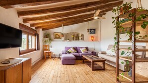 A cozy living room with wooden beams, a sofa, a coffee table, and a TV. - Holiday Home 'Romegosa Benestar' with Mountain Views, Wi-Fi, and Air Conditioning (Sant Marçal)