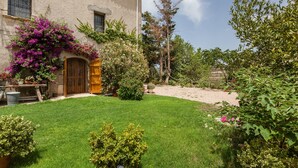 A house with a well-maintained lawn, a wooden door, and a garden with various plants and trees. - Holiday Home 'Romegosa Benestar' with Mountain Views, Wi-Fi, and Air Conditioning (Sant Marçal)