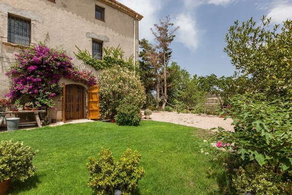 A house with a well-maintained lawn, a wooden door, and a garden with various plants and trees.