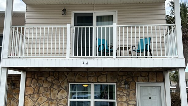 Un immeuble de deux étages doté d’un balcon, d’une façade en pierre et d’une porte portant le numéro 34.