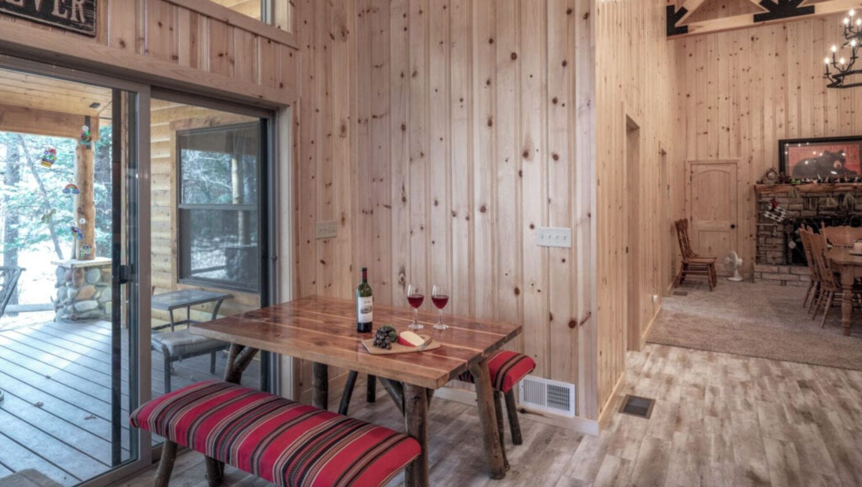 Un interior de madera con una mesa de comedor preparada para dos personas, un banco y una chimenea.