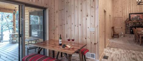 Un interior de madera con una mesa de comedor preparada para dos personas, un banco y una chimenea.