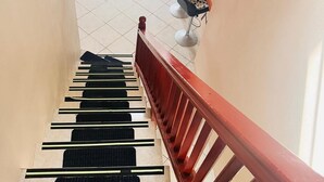 A staircase with a red handrail and black and white striped steps. - Nature's Luxurious Living (Roseau)