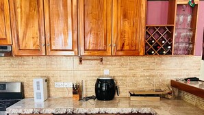 A kitchen with wooden cabinets, a black slow cooker, and a wine rack. - Nature's Luxurious Living (Roseau)