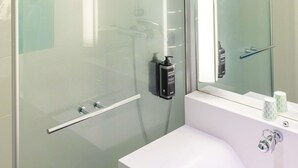 Une salle de bain moderne avec une douche à parois de verre, un lavabo blanc et un miroir.