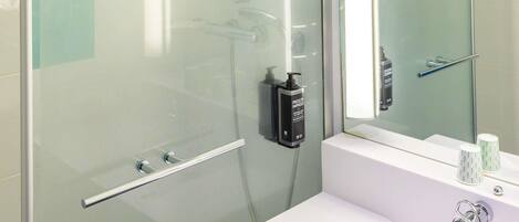 A modern bathroom with a glass shower enclosure, a white sink, and a mirror.