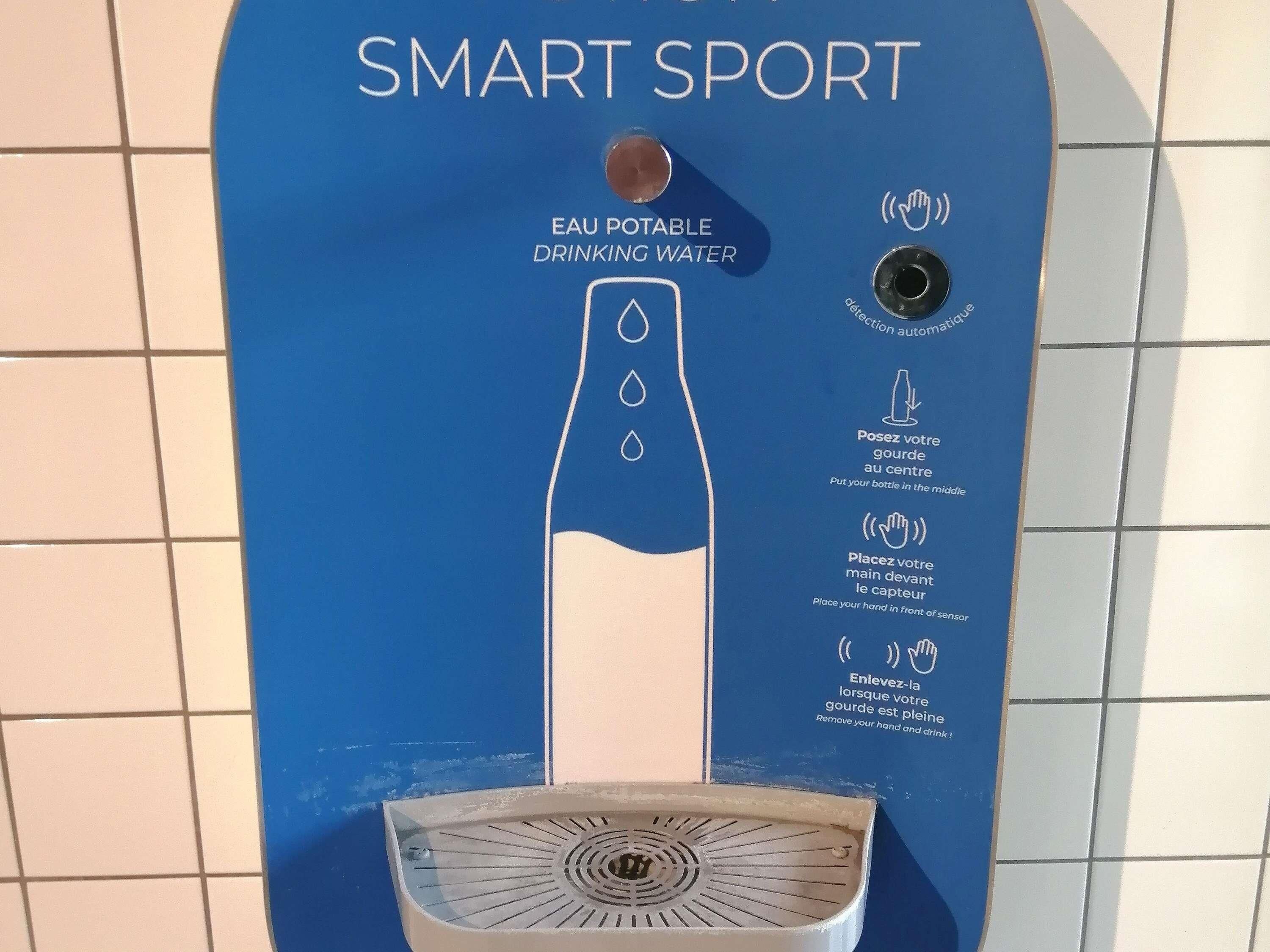 Dispensador de agua azul con instrucciones de uso, un sensor de movimiento y un grifo dosificador.