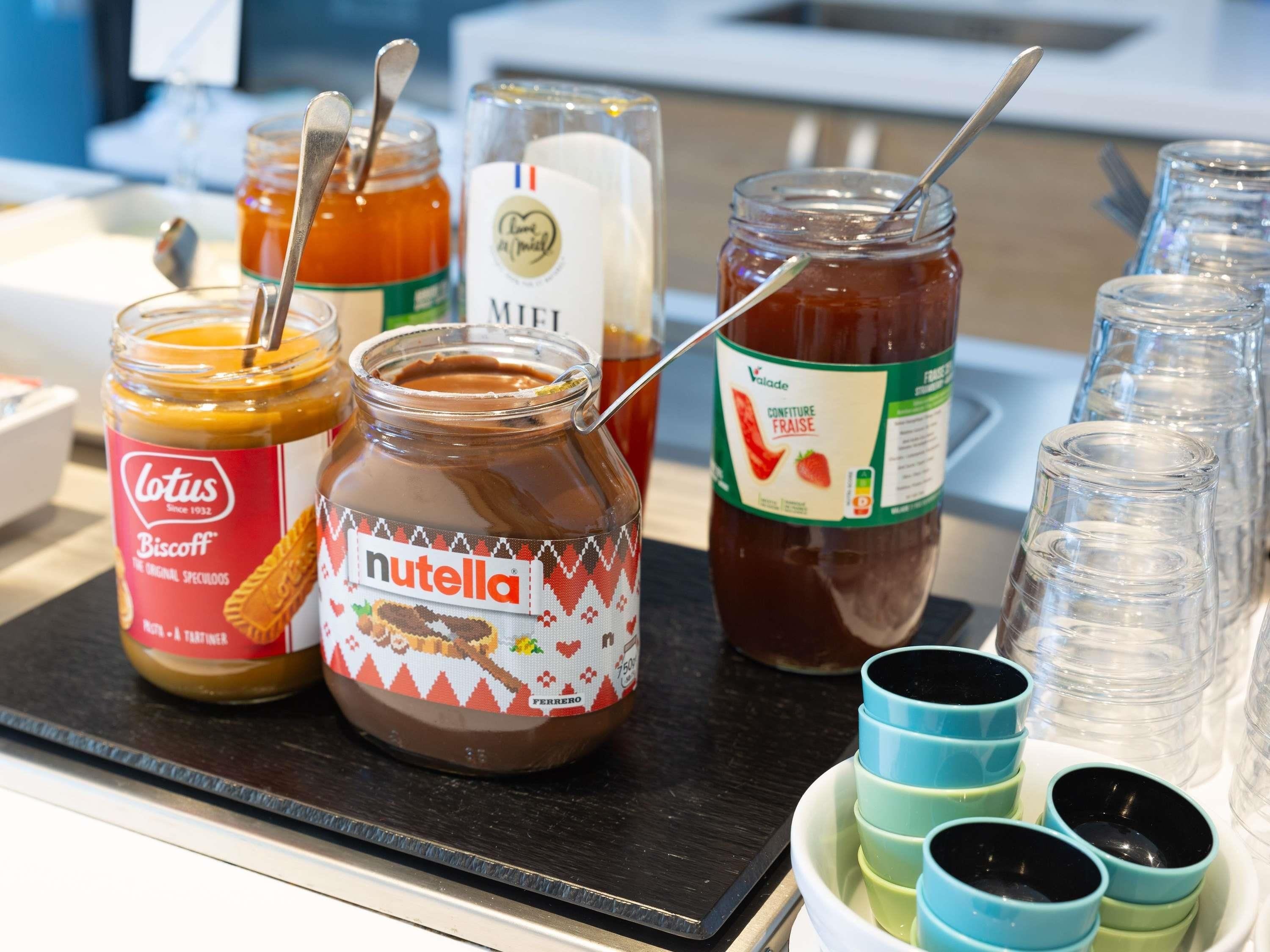 Variedad de alimentos, incluyendo frascos de Nutella, Miele y otras opciones para untar, sobre una mesa.