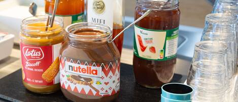 Variedad de alimentos, incluyendo frascos de Nutella, Miele y otras opciones para untar, sobre una mesa.