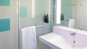 Une salle de bain moderne avec une douche à parois de verre, un lavabo blanc et un grand miroir.