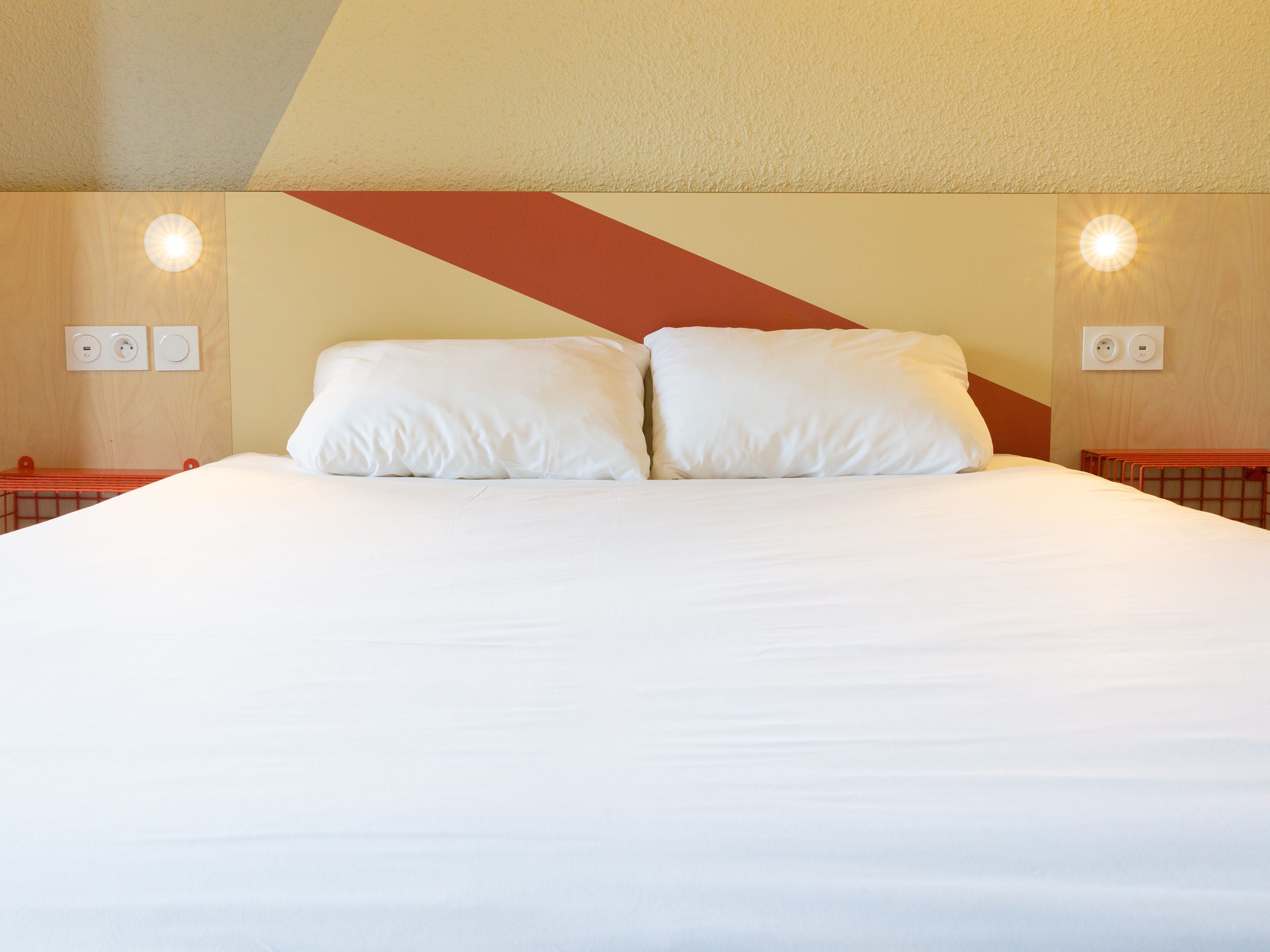 A neatly made bed with two pillows in a hotel room.