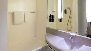 Une salle de bain moderne avec une baignoire, un lavabo et un grand miroir.