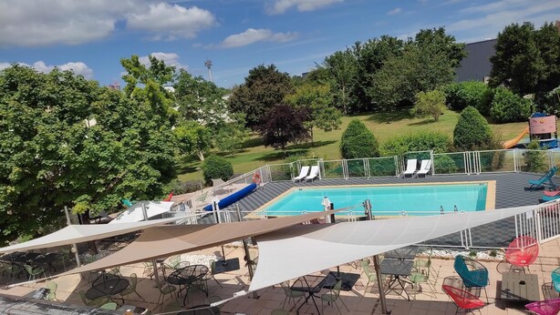 Un espace piscine sur le toit, équipé d’un toboggan, de chaises longues et de coins salon extérieurs.