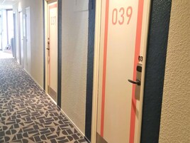A hotel corridor with numbered doors, patterned floor, and a textured wall.