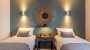 Habitación de hotel con dos camas, una mesita de noche con lámpara y un adorno en la pared.
