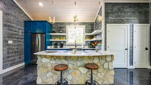 A kitchen with a stone island, blue cabinets, and a white door. - Butterfly Kisses- Perfect Honeymoon Cabin! (Broken Bow)