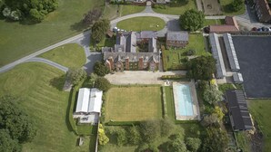 Oversigtsbillede af en boligejendom med et stort hus, en swimmingpool og en tennisbane.