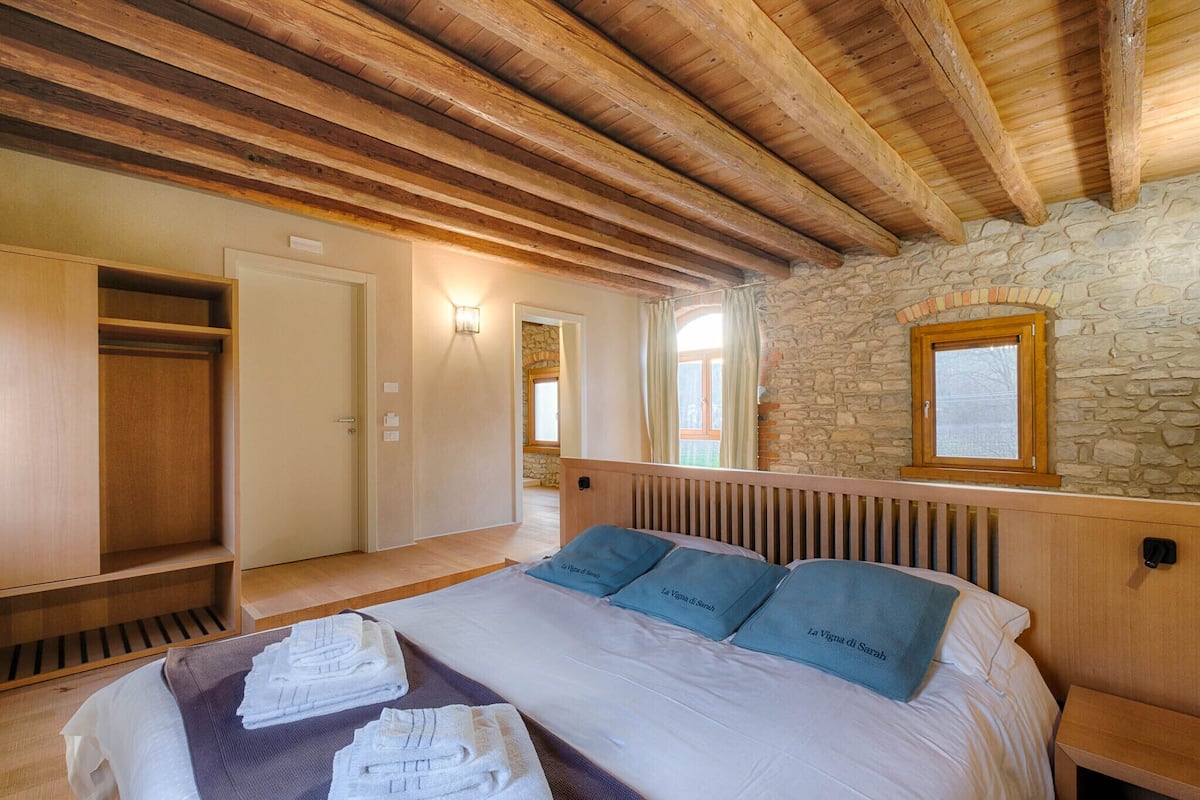 Ein Schlafzimmer mit Holzboden, Steinwand und einem Bett mit blauen Kissen.