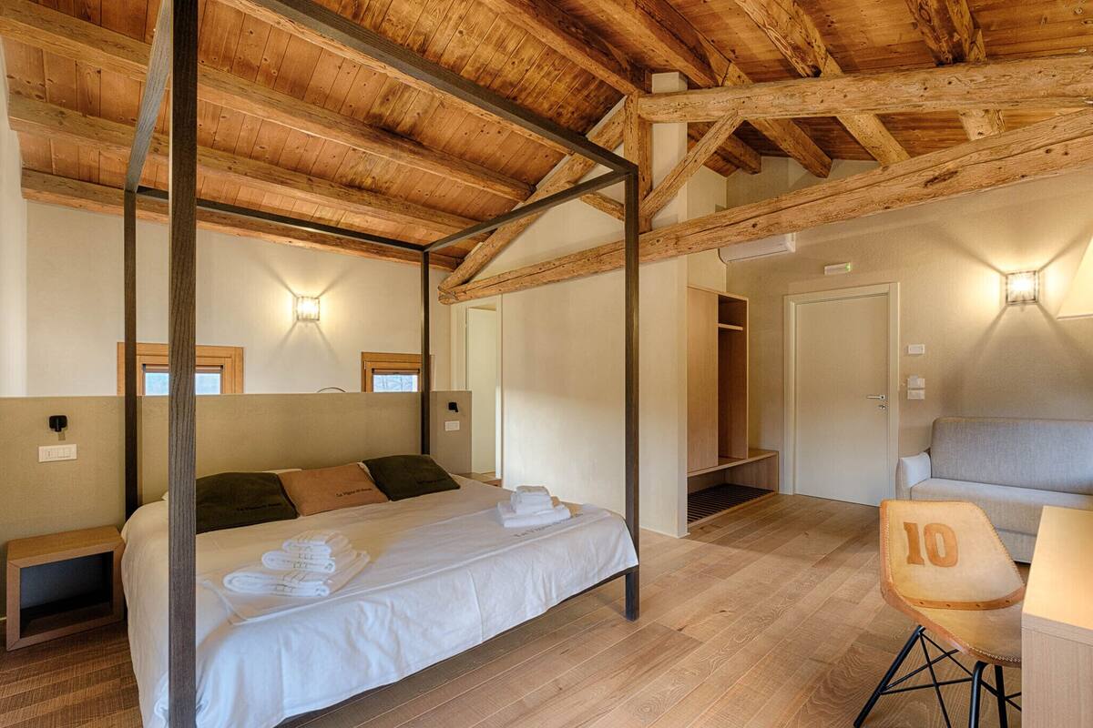 Ein Schlafzimmer mit Holzboden, einem Bett mit weißen Leinen, einem Stuhl mit einer Nummer und einem Sofa.