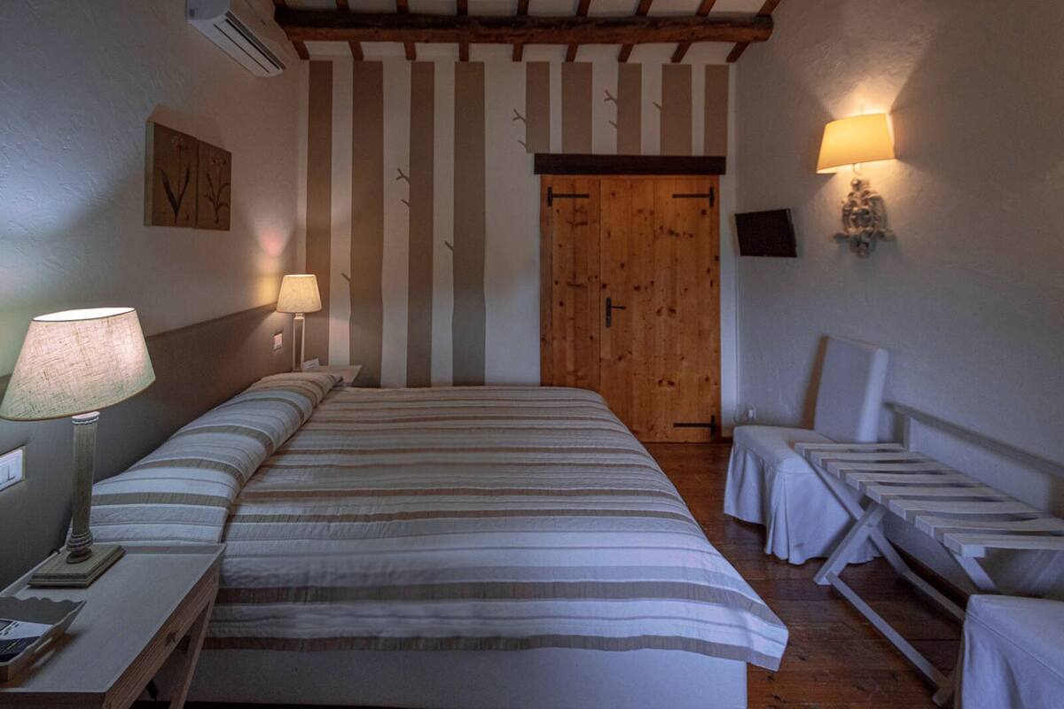 Ein Schlafzimmer mit einem großen Bett, zwei Nachttischlampen, einer Holztür und einem kleinen Tisch mit Lampe.