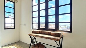 Une pièce avec une grande fenêtre, un bureau en bois et une chaise.