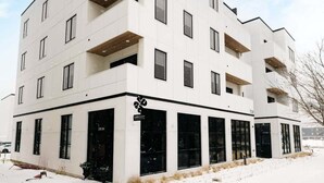 Un immeuble moderne à plusieurs étages, doté d’un toit plat, de grandes fenêtres et de balcons.