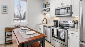Une cuisine moderne avec des meubles blancs, un four à micro-ondes encastré, une cuisinière et un lave-vaisselle.