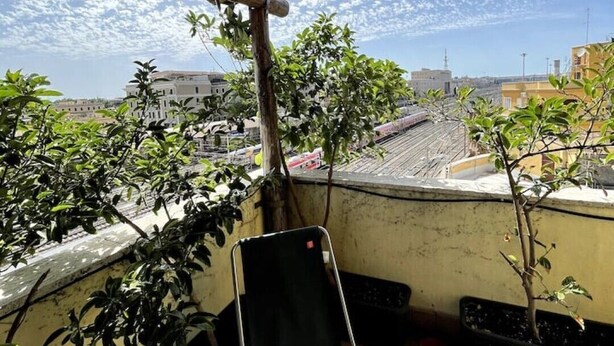 A balcony with a wooden ceiling, potted plants, and a metal chair. - Loft SanLorenzo (Roma)