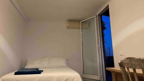 A small, well-lit bedroom with a bed, a chair, and a sliding glass door leading to an outdoor area. - Loft SanLorenzo (Roma)