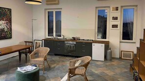 A modern kitchen with a dining area, featuring a large window, a gas stove, and wicker chairs. - Loft SanLorenzo (Roma)
