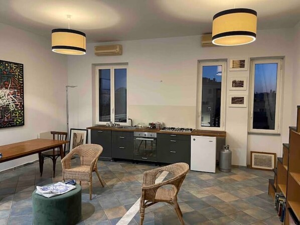 Een moderne keuken met een eetgedeelte, met een groot raam, een gasfornuis en rieten stoelen.