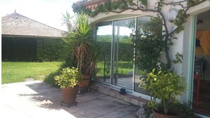 A house with a tiled roof, a glass door, and potted plants.
