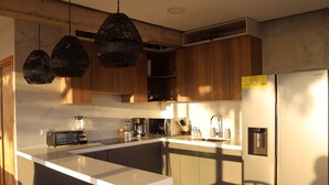 Une cuisine moderne avec un plan de travail blanc, des armoires en bois et un réfrigérateur en acier inoxydable.